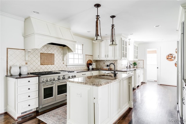 kitchen featuring custom range hood, white cabinetry, crown molding, range with two ovens, and glass insert cabinets