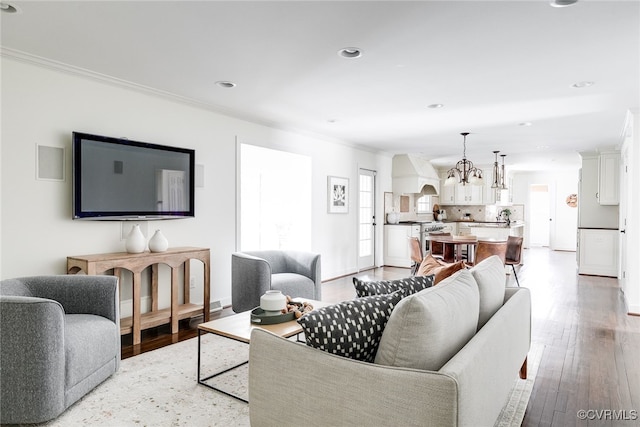 living room featuring baseboards, recessed lighting, light wood-style floors, crown molding, and a notable chandelier