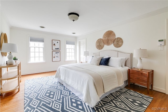 bedroom featuring crown molding, wood finished floors, visible vents, and baseboards