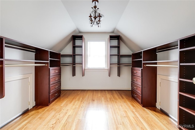 walk in closet with light wood finished floors and lofted ceiling