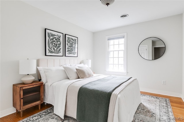 bedroom with visible vents, baseboards, and wood finished floors