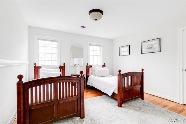 bedroom with visible vents, baseboards, and wood finished floors