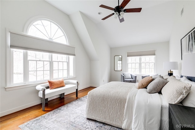 bedroom with lofted ceiling, multiple windows, and wood finished floors