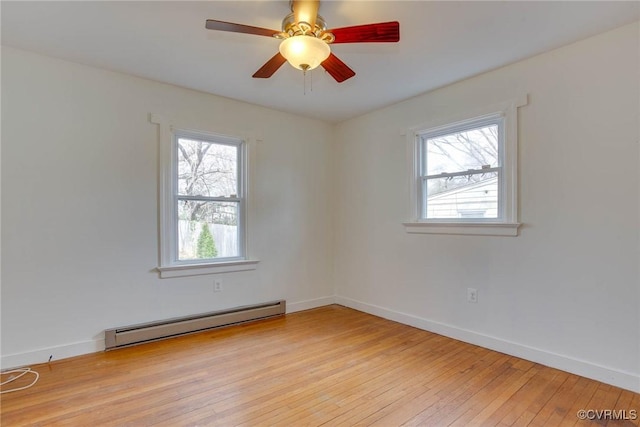 empty room with light wood finished floors, baseboard heating, a ceiling fan, and baseboards