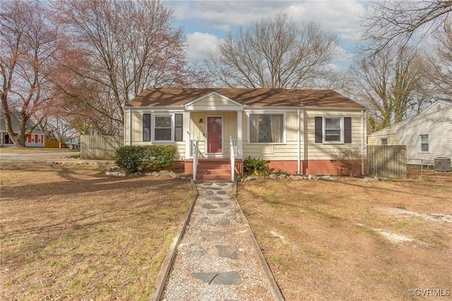 bungalow-style house featuring central air condition unit, a front lawn, and fence