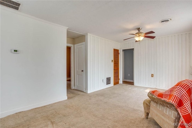 unfurnished room with visible vents, baseboards, light colored carpet, and a ceiling fan