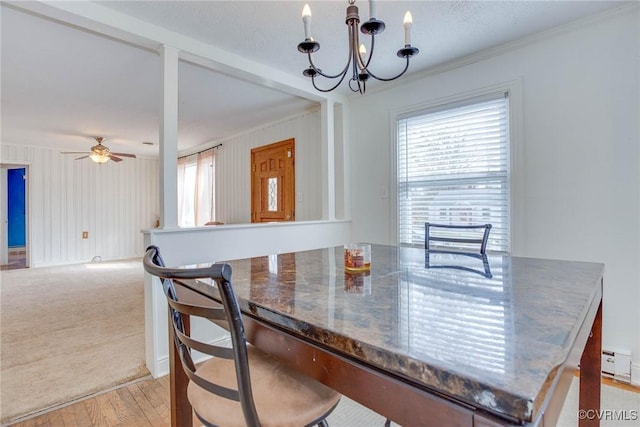 dining space featuring ceiling fan with notable chandelier, light colored carpet, light wood-style flooring, and ornamental molding