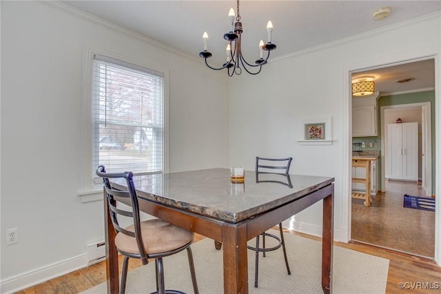 dining space with light wood-style flooring, a notable chandelier, and ornamental molding