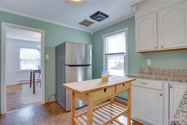 kitchen featuring a baseboard radiator, ornamental molding, white cabinets, and freestanding refrigerator