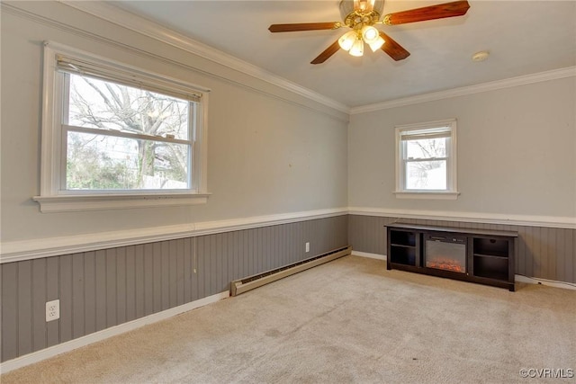 carpeted spare room with baseboard heating, ornamental molding, and a wainscoted wall