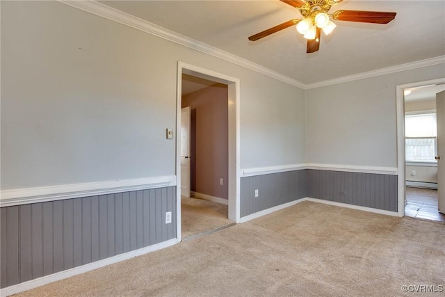 empty room with a ceiling fan, carpet floors, wainscoting, crown molding, and a baseboard radiator