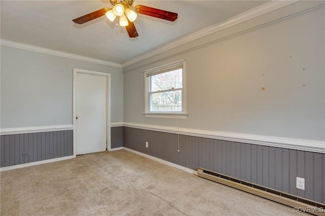 carpeted spare room with a baseboard heating unit, ornamental molding, and wainscoting