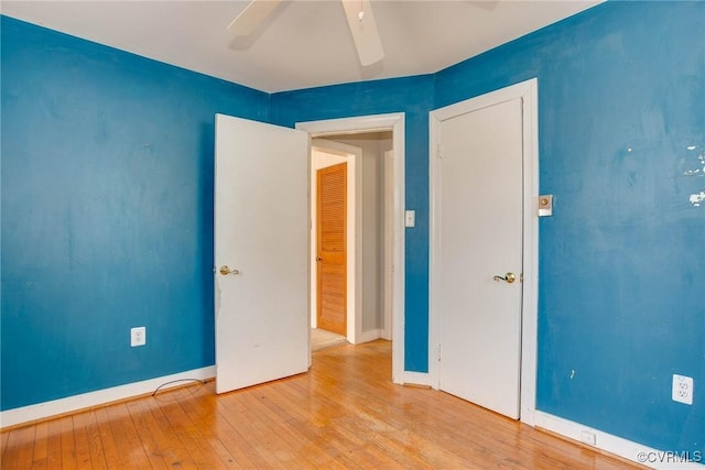 unfurnished bedroom featuring hardwood / wood-style floors, a ceiling fan, and baseboards