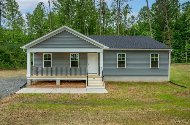 view of front of property featuring covered porch, a front yard, and a shingled roof