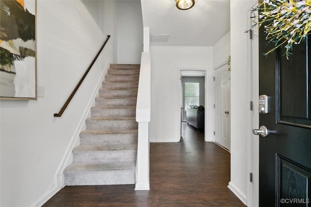 entryway featuring baseboards, wood finished floors, and stairs