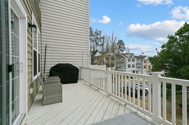 wooden terrace with a residential view and a grill