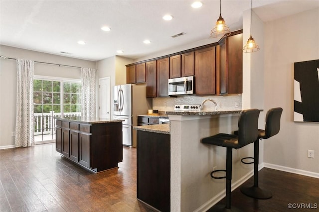 kitchen featuring stainless steel appliances, dark wood-type flooring, visible vents, and decorative backsplash