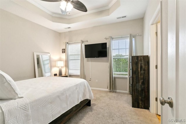 carpeted bedroom featuring a tray ceiling, visible vents, baseboards, and crown molding