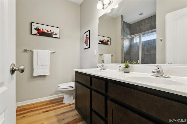 full bathroom featuring a sink, toilet, wood finished floors, and a shower stall