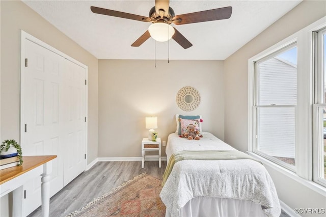 bedroom with a ceiling fan, multiple windows, wood finished floors, and baseboards