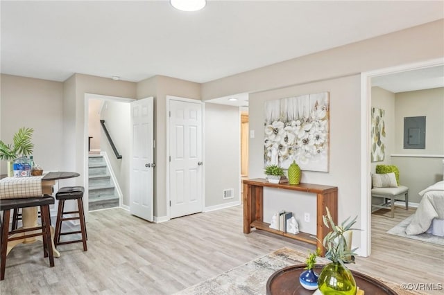 interior space with visible vents, electric panel, stairway, light wood-style floors, and baseboards