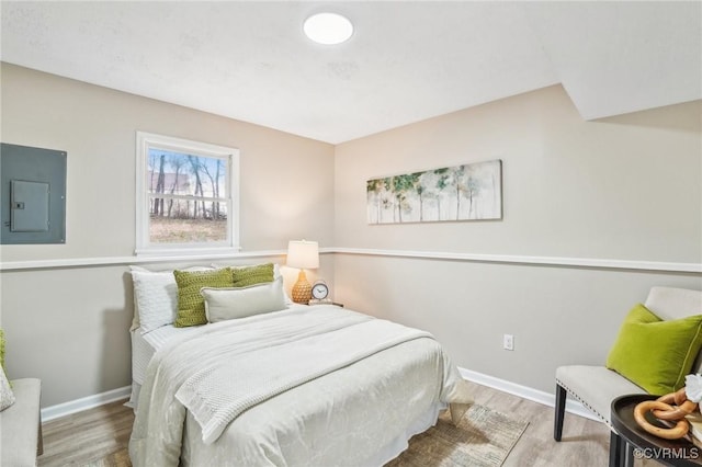 bedroom featuring electric panel, wood finished floors, and baseboards