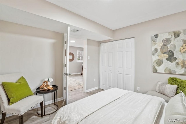 bedroom featuring wood finished floors, visible vents, a closet, and baseboards