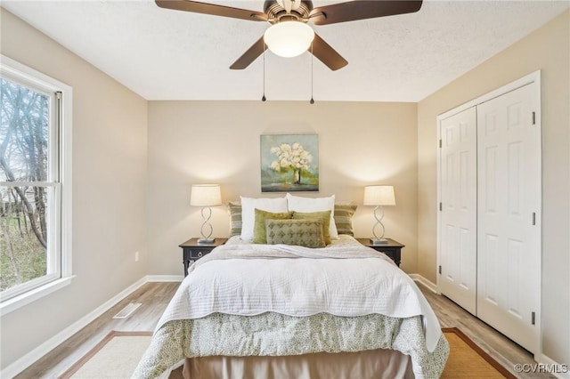 bedroom featuring a closet, baseboards, light wood-style floors, and a ceiling fan