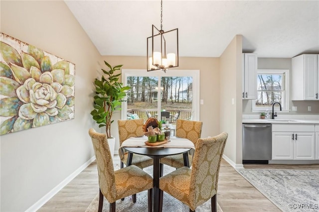 dining room featuring an inviting chandelier, baseboards, and light wood-type flooring