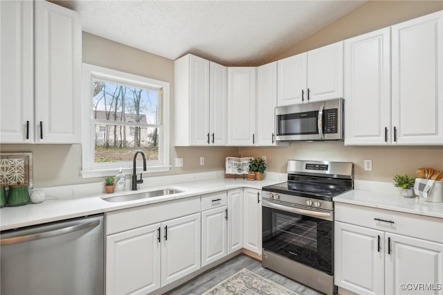 kitchen featuring a sink, appliances with stainless steel finishes, and white cabinets