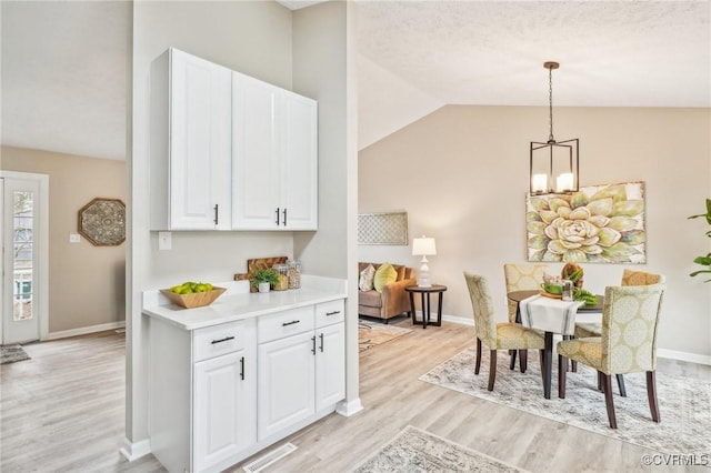 dining room featuring visible vents, baseboards, lofted ceiling, a notable chandelier, and light wood-type flooring