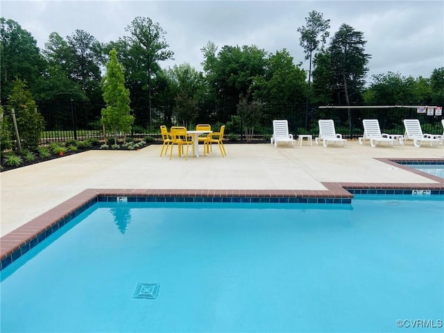 community pool with a patio area and fence