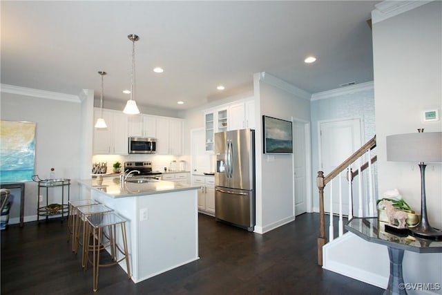 kitchen with ornamental molding, appliances with stainless steel finishes, a breakfast bar area, a peninsula, and glass insert cabinets