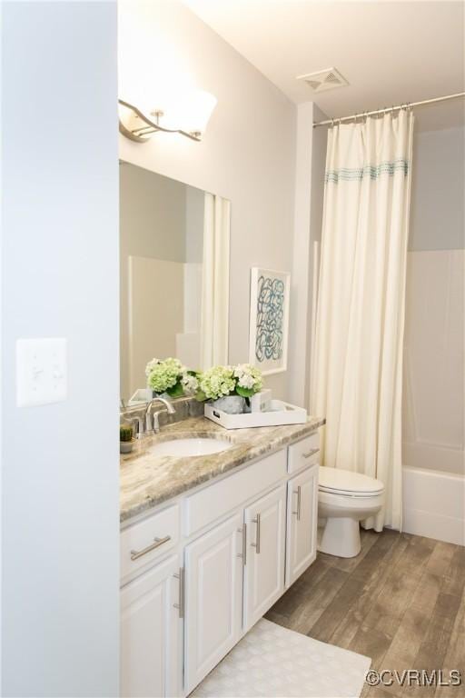 full bathroom featuring visible vents, toilet, shower / bath combo, wood finished floors, and vanity