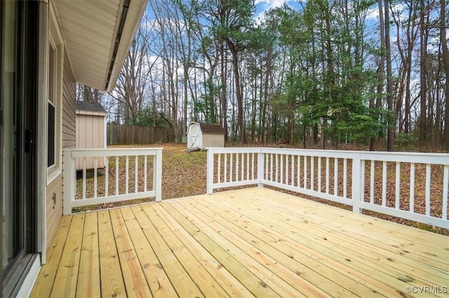 wooden deck with a storage unit, an outbuilding, and fence