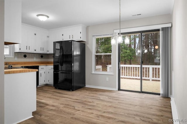 kitchen with white cabinets, tasteful backsplash, visible vents, and freestanding refrigerator