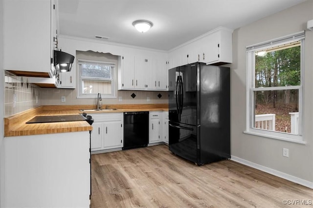 kitchen featuring tasteful backsplash, light wood-style flooring, white cabinets, black appliances, and a sink