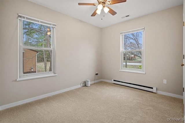 spare room featuring a baseboard heating unit, baseboards, visible vents, and carpet floors