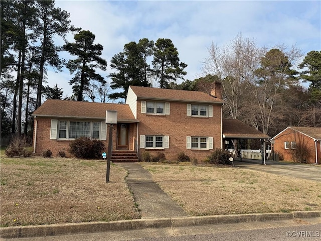 split level home with an attached carport, driveway, a chimney, and a front lawn