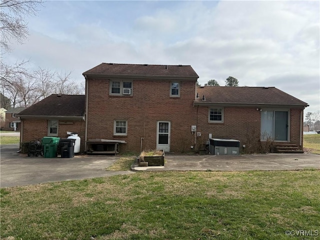 back of house featuring a yard, entry steps, brick siding, and a patio area