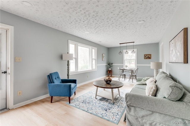 living area with wood finished floors, baseboards, and a textured ceiling