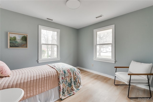 bedroom with light wood-type flooring, visible vents, and baseboards