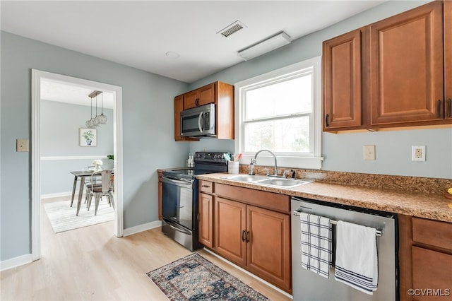 kitchen with visible vents, light wood-style floors, brown cabinetry, stainless steel appliances, and a sink