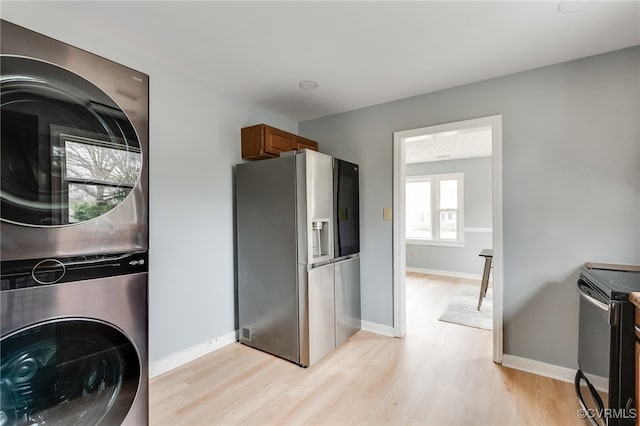 kitchen featuring electric range, stainless steel fridge, light wood-style floors, brown cabinetry, and stacked washer / drying machine