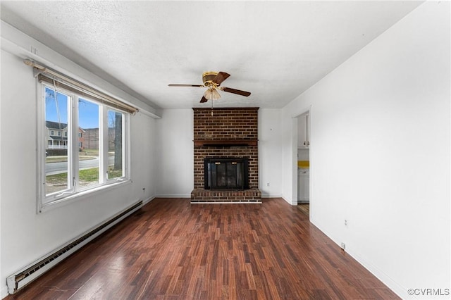 unfurnished living room with a brick fireplace, a baseboard heating unit, baseboards, ceiling fan, and dark wood-style floors