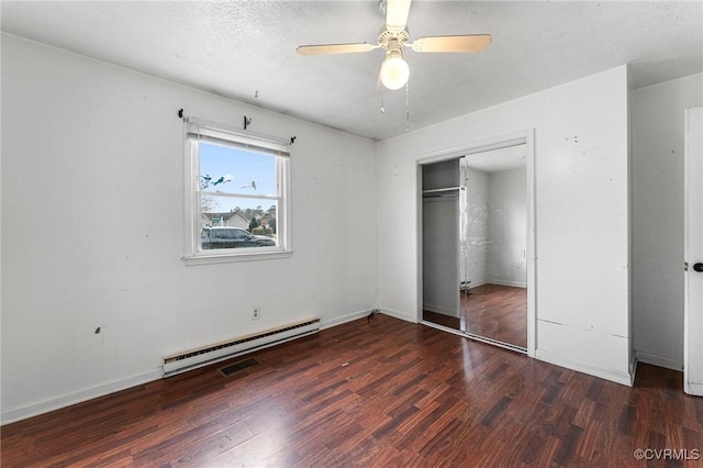 unfurnished bedroom featuring wood finished floors, baseboards, a closet, a textured ceiling, and baseboard heating