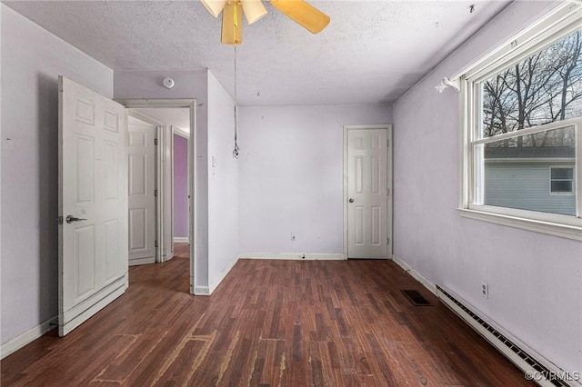 empty room featuring a ceiling fan, visible vents, wood finished floors, baseboards, and baseboard heating