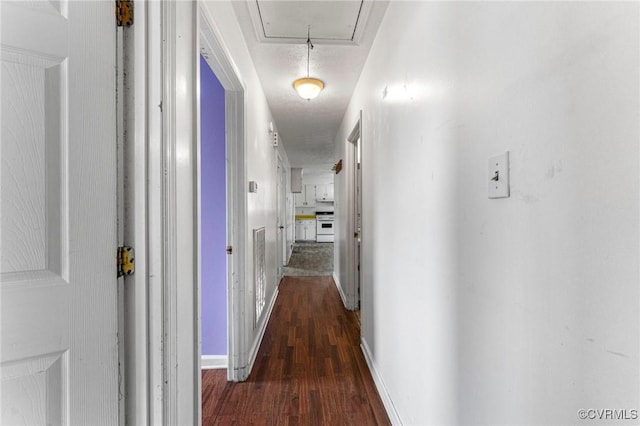 corridor with attic access, wood finished floors, and baseboards