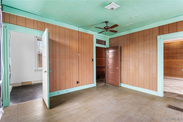 unfurnished bedroom featuring tile patterned floors, wooden walls, baseboards, and visible vents