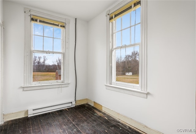 empty room with a baseboard heating unit, plenty of natural light, and dark wood finished floors